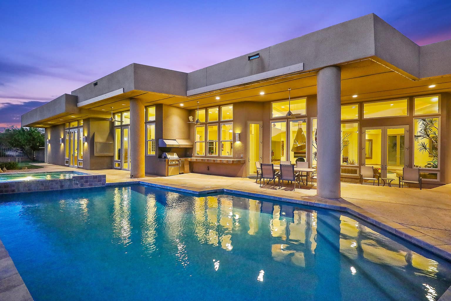 A modern pool home glowing at dusk in the Coachella Valley